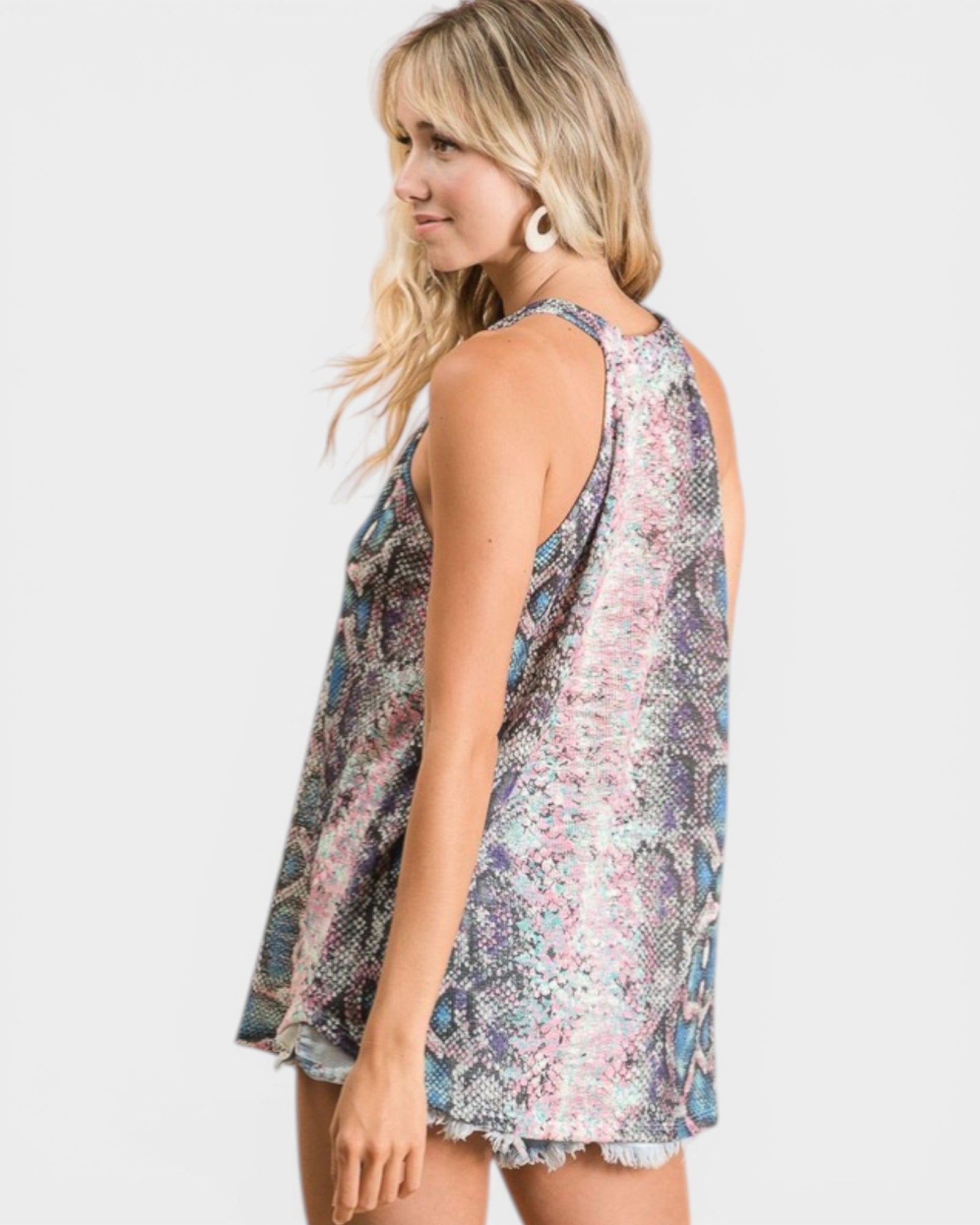 Woman wearing a sleeveless, patterned top on a white background
