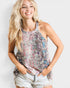 Woman wearing a patterned tank top and denim shorts against a plain background