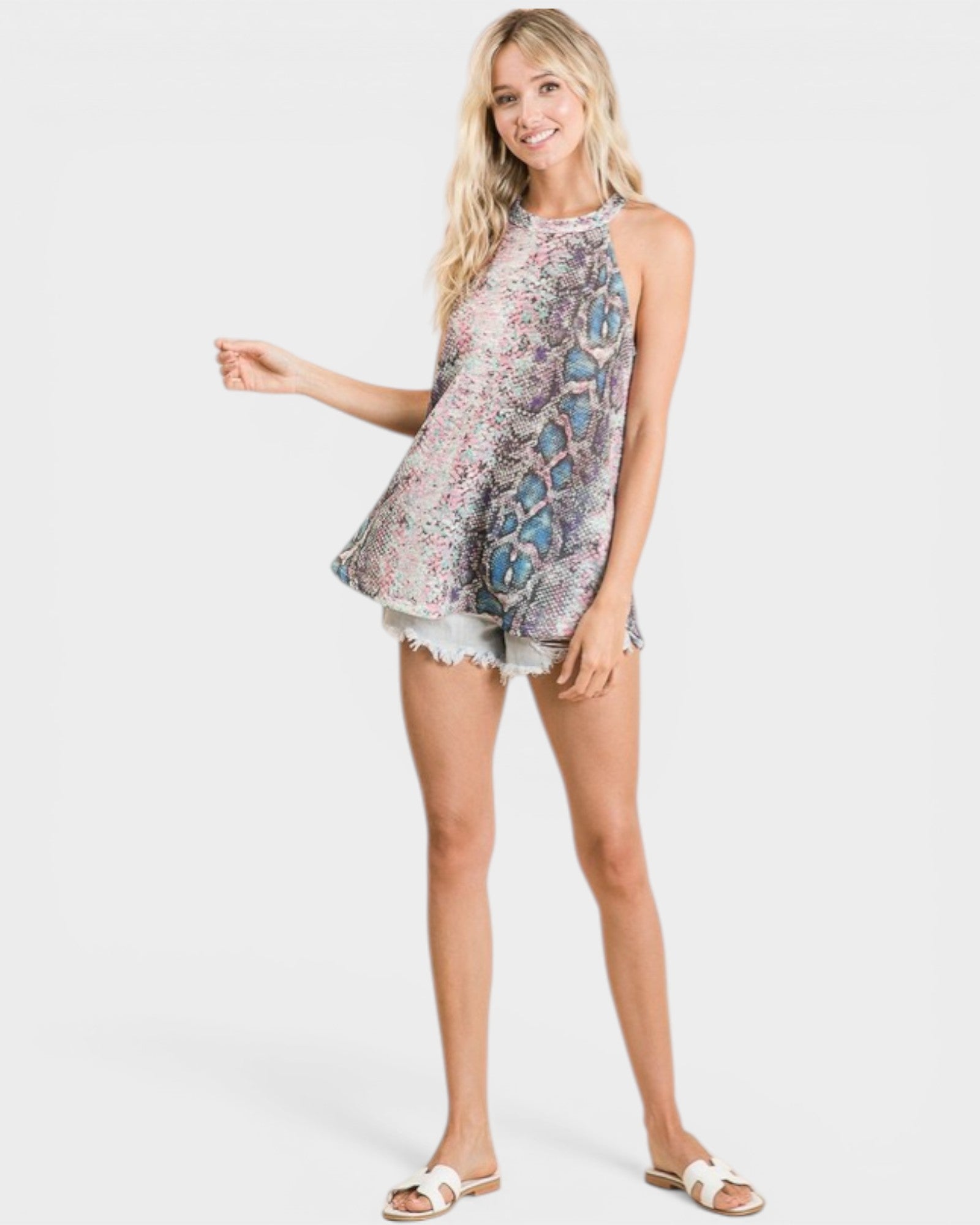 Woman wearing a sleeveless floral top and denim shorts on a white background