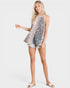 Woman wearing a sleeveless floral top and denim shorts on a white background