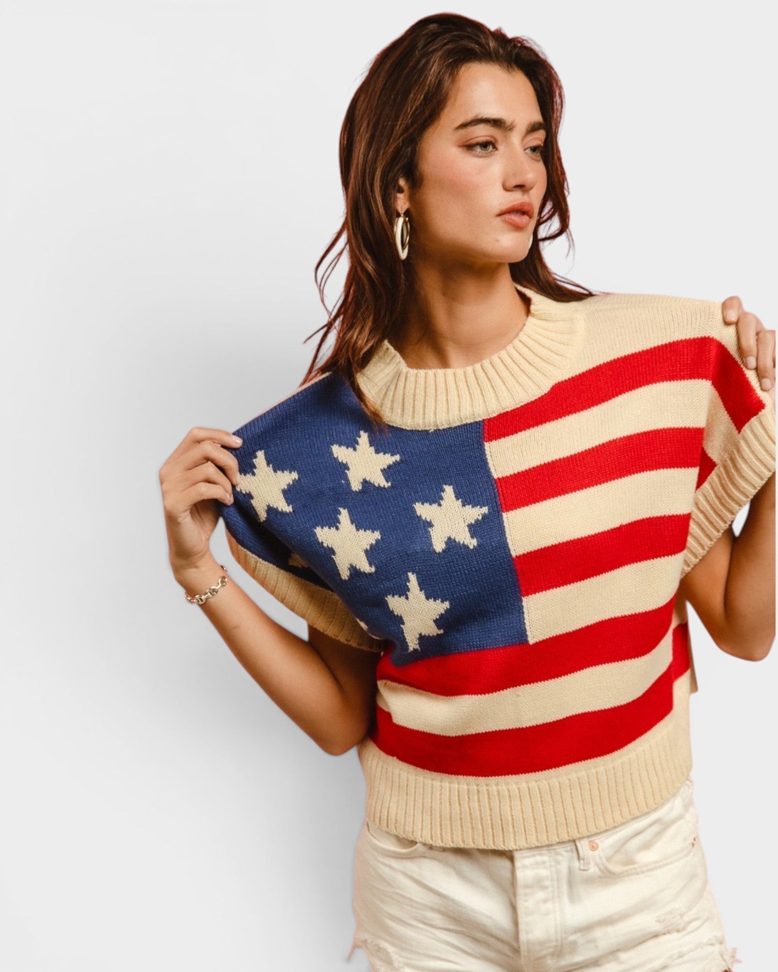 Woman wearing a sweater with an American flag design on a plain background