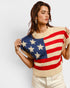 Woman wearing a sweater with an American flag design on a plain background