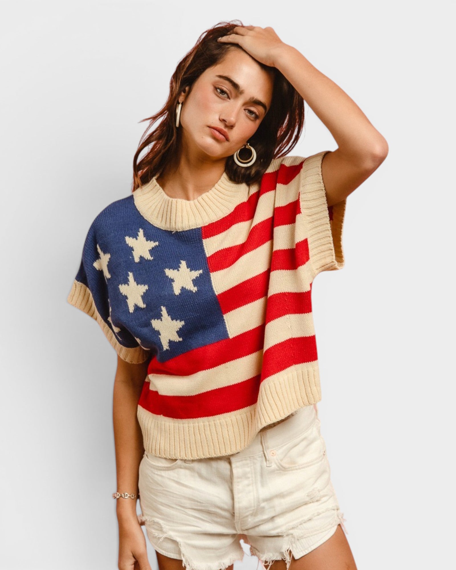 Woman wearing a sweater with an American flag design on a plain background