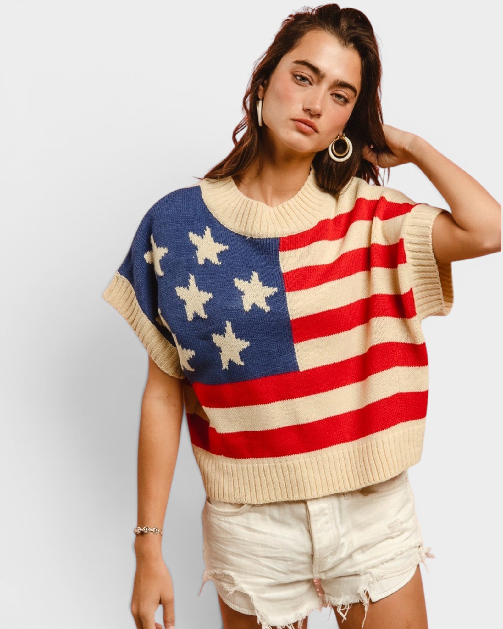 Person wearing a sweater with an American flag design on a plain background