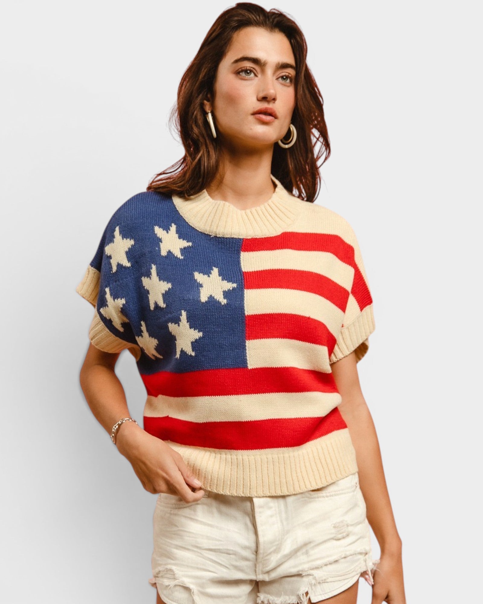 Woman wearing a sweater with an American flag design on a plain background