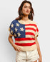 Woman wearing a sweater with an American flag design on a plain background