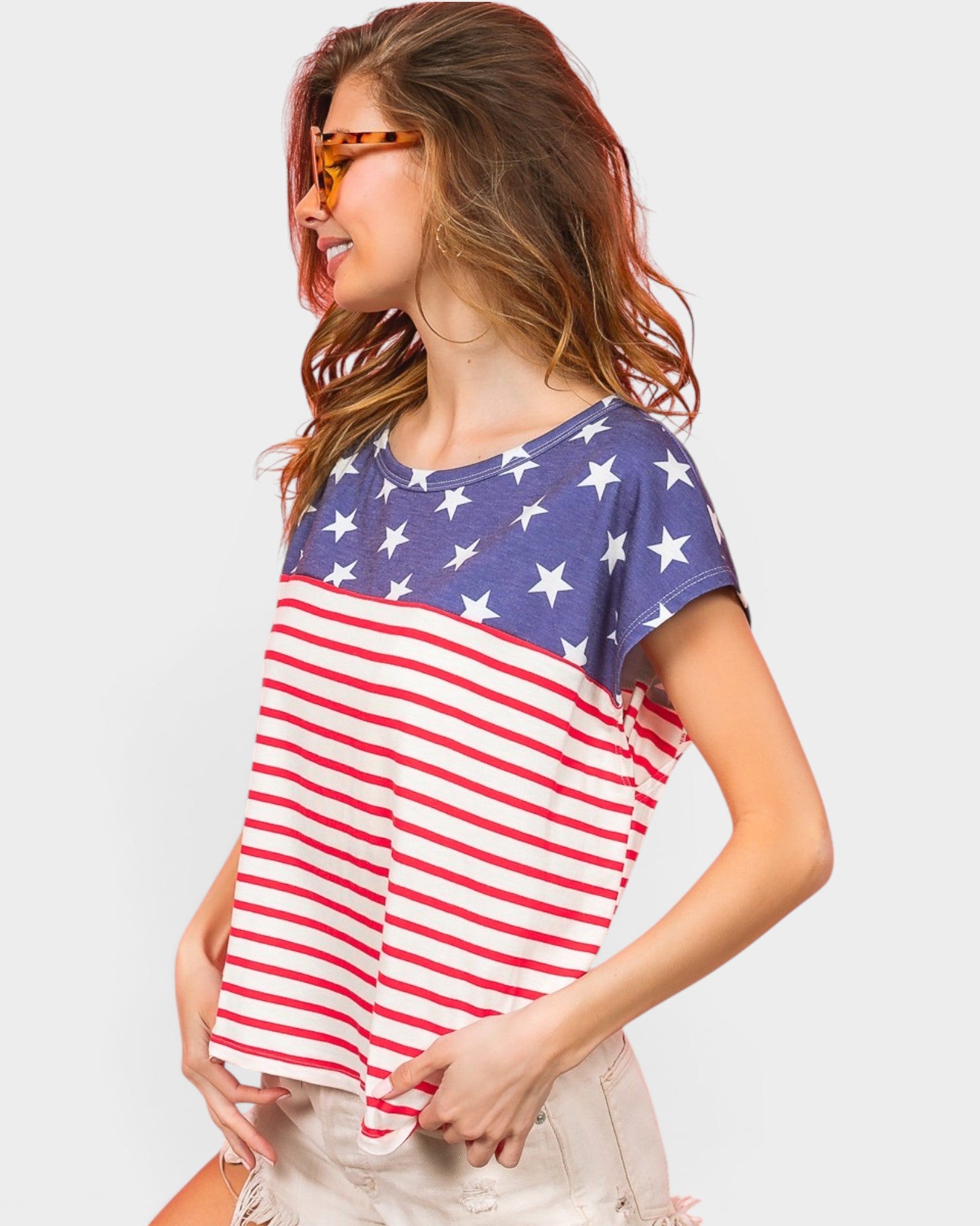 Woman wearing an American flag t-shirt on a plain background