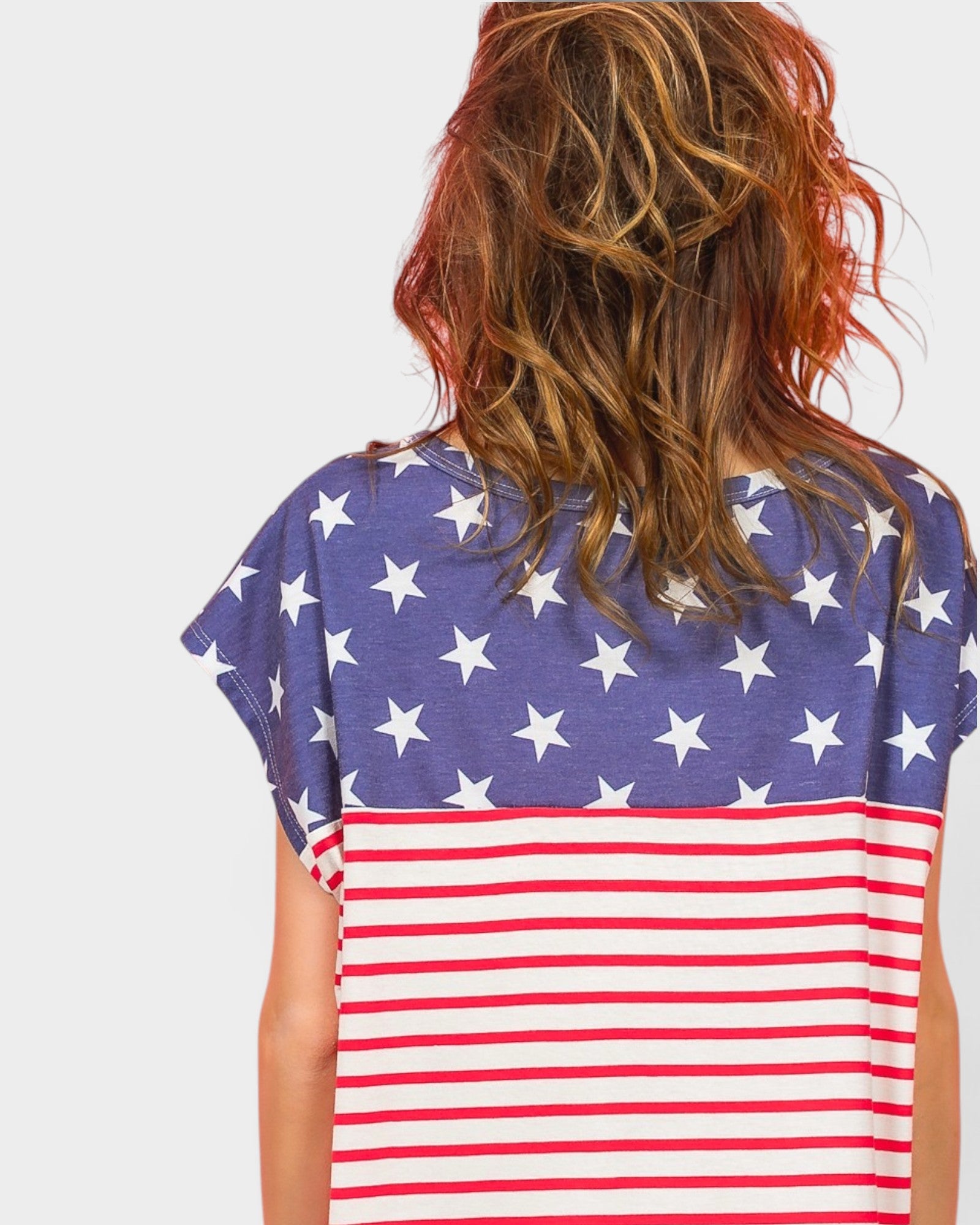 Person wearing a shirt with American flag design on a plain background