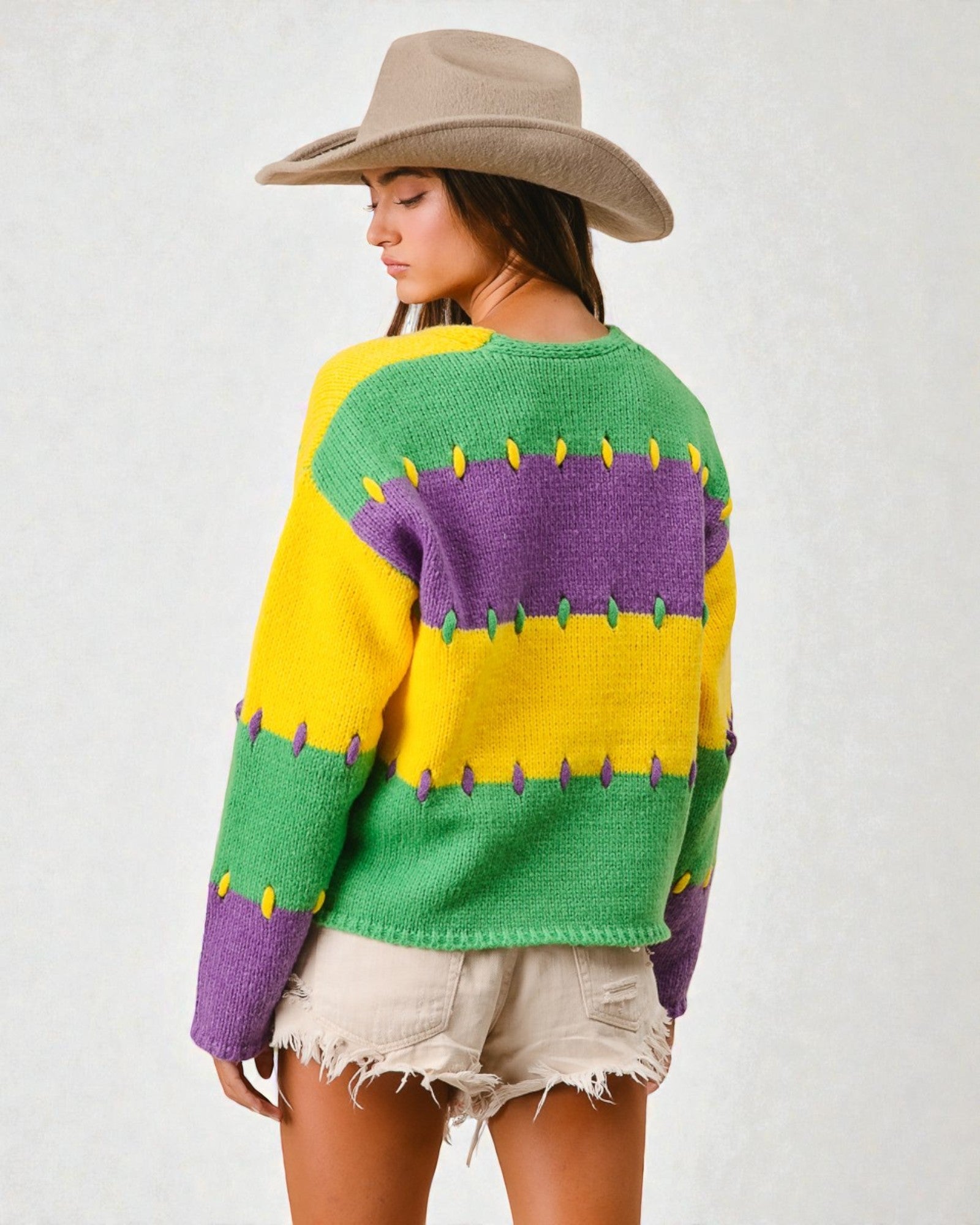 Person wearing a colorful sweater with green, yellow, and purple stripes on a white background