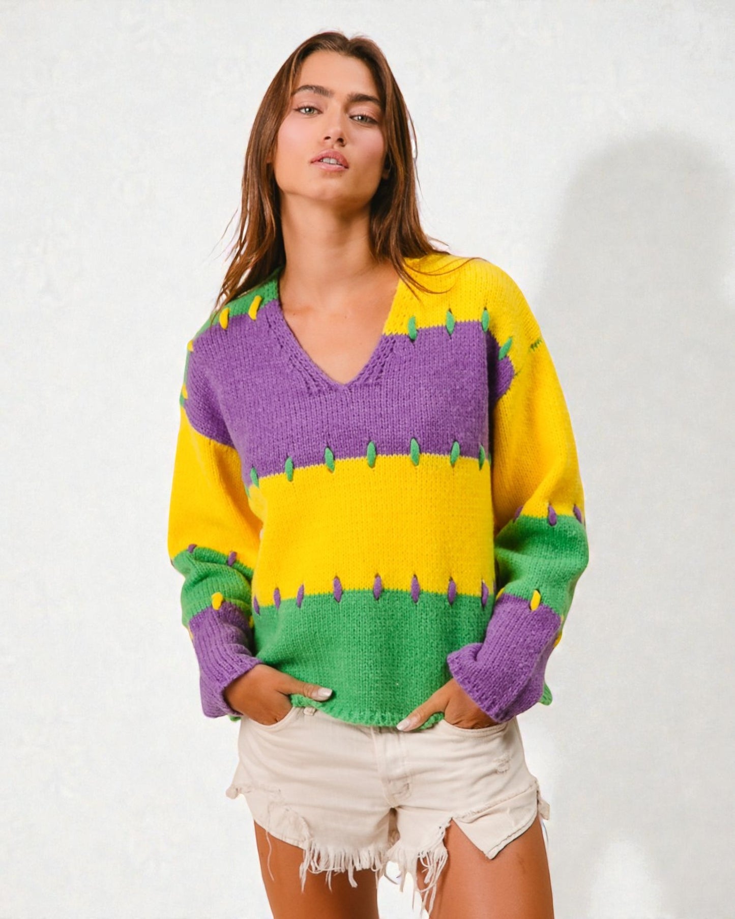 Woman wearing a colorful sweater with purple, yellow, and green patterns on a white background
