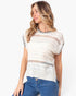 A woman wearing a short-sleeve knit top with a cream base and black striped trim on the sleeves and crew neck, paired with blue jeans, against a plain white background.