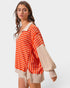 Woman wearing an orange and white striped shirt with beige sleeves and shorts on a white background