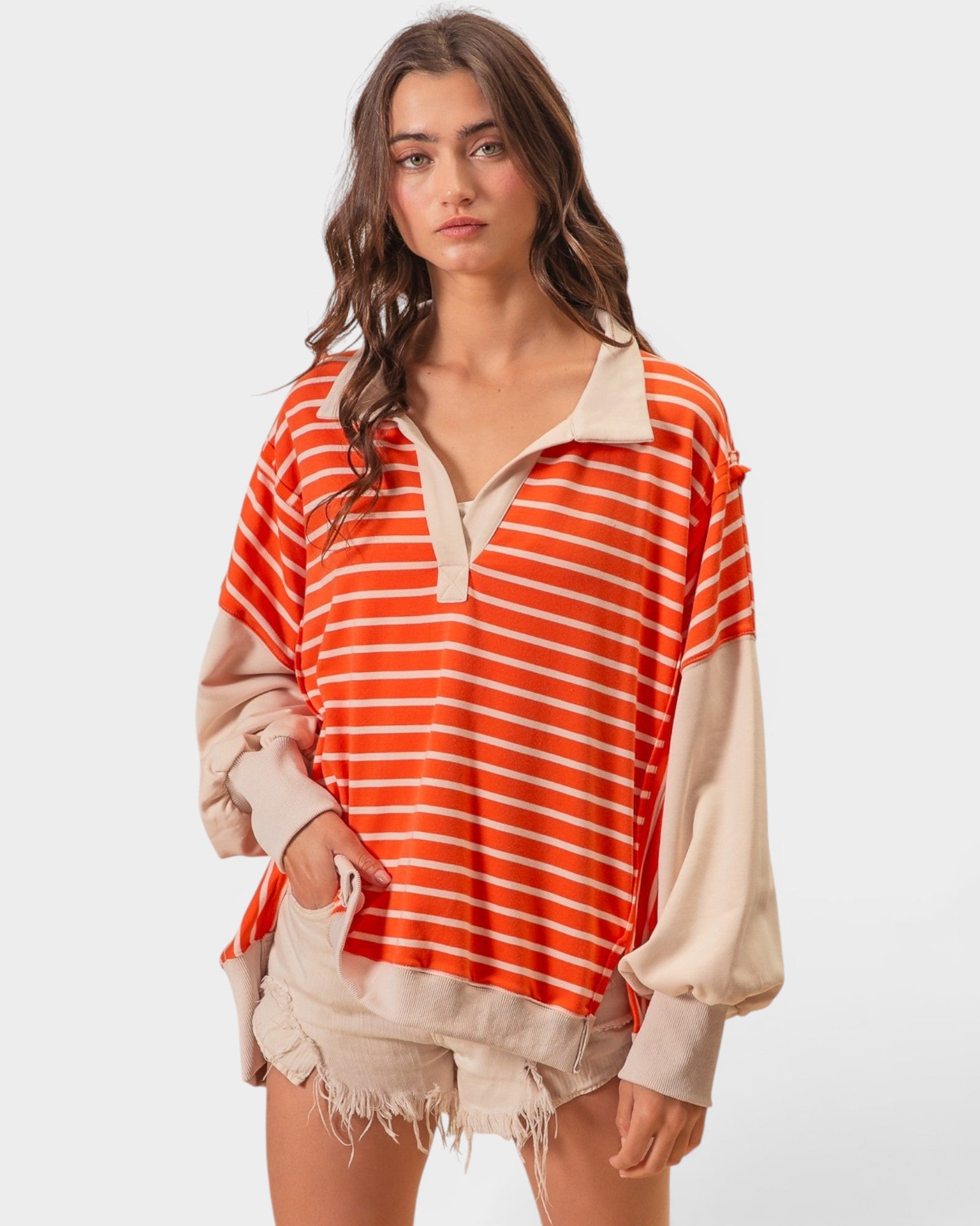 Woman wearing an orange and beige striped shirt with a white background