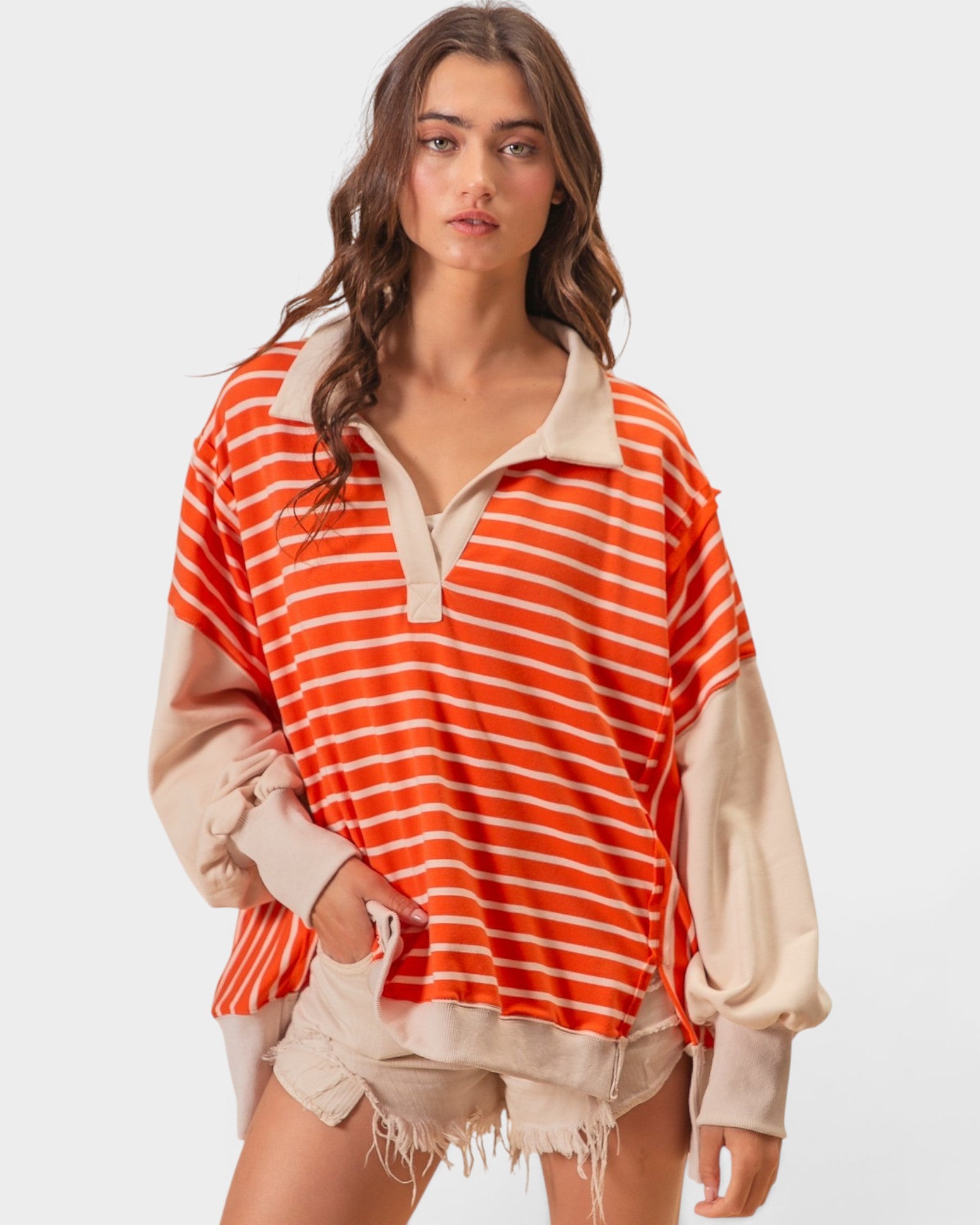 Woman wearing a red and white striped shirt with beige accents on a plain background