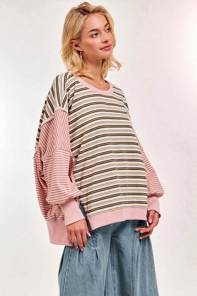 Woman wearing a striped sweater with pink sleeves and blue jeans on a white background