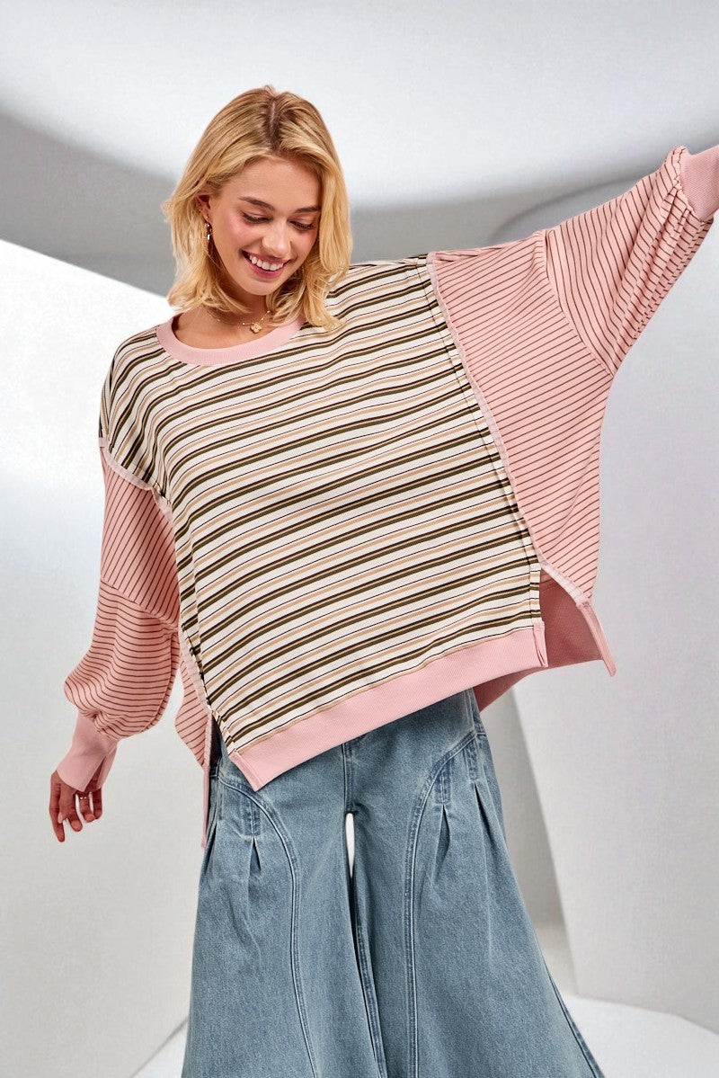 Woman wearing a pink and striped sweater with a white background