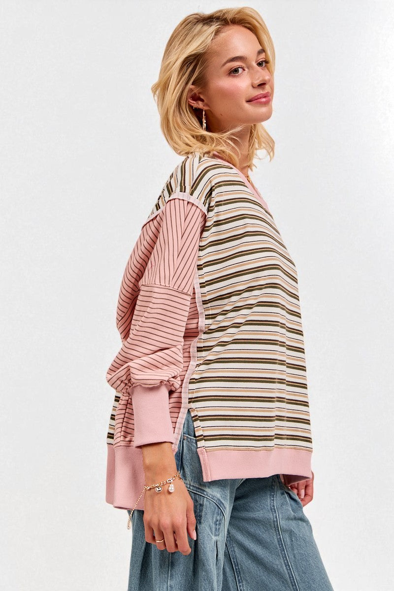 Woman wearing a striped sweater with pink sleeves on a white background