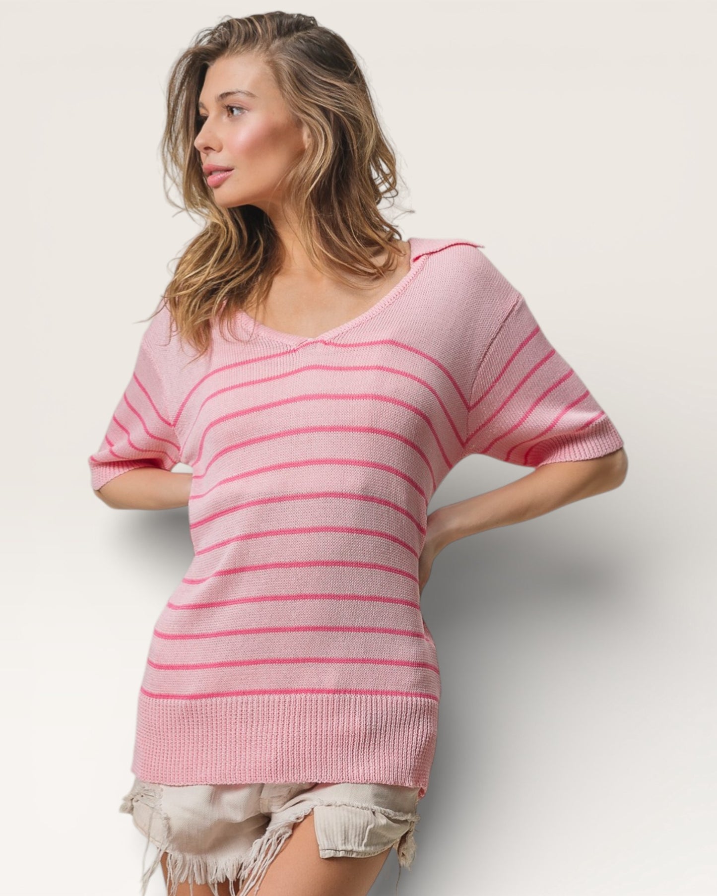 Woman wearing a pink striped sweater against a plain background