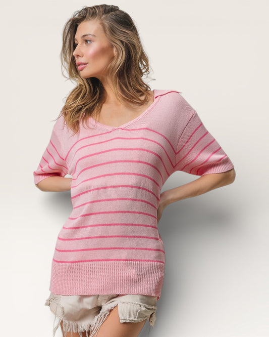 Woman wearing a pink striped sweater against a plain background