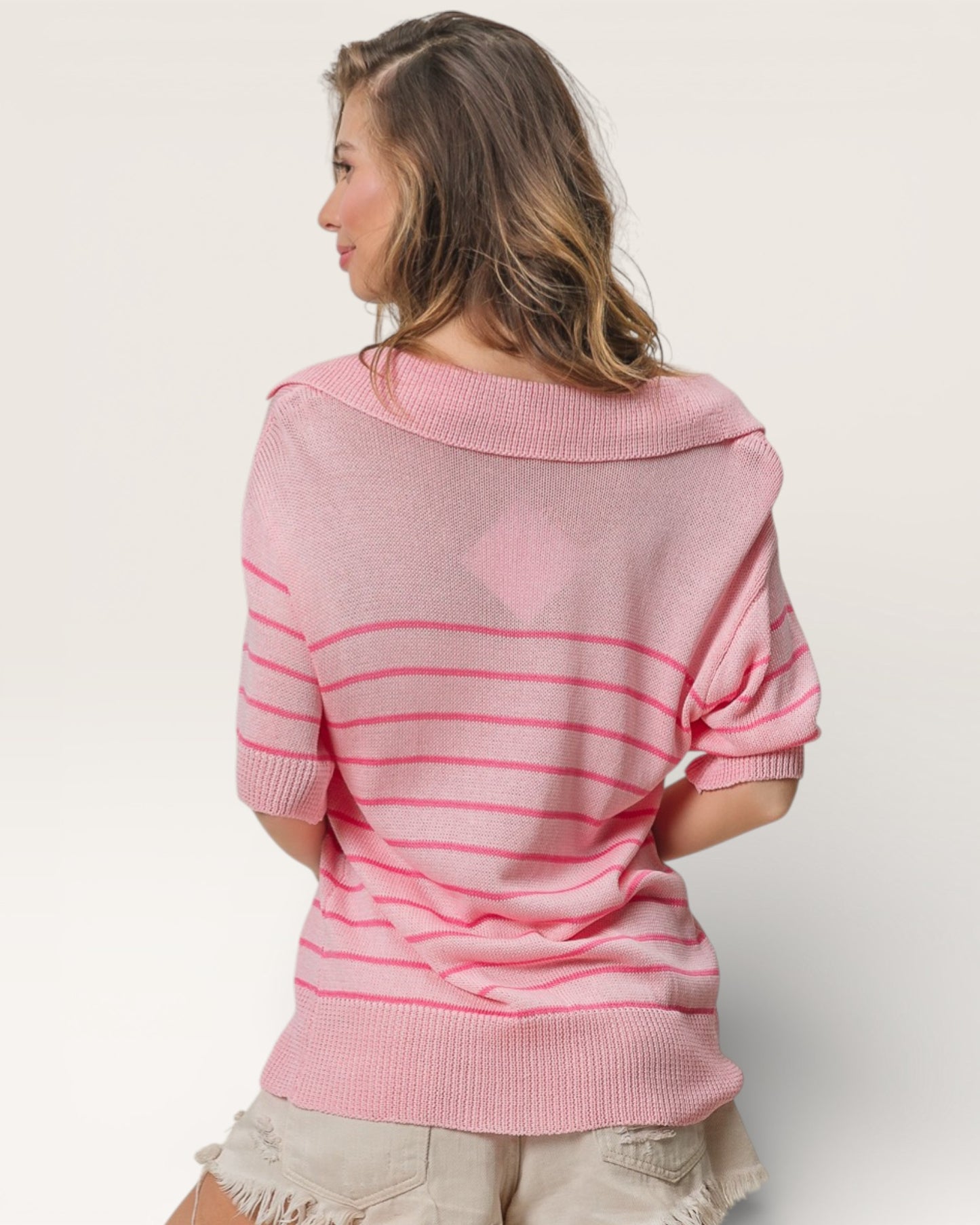 Woman wearing a pink striped sweater against a plain background