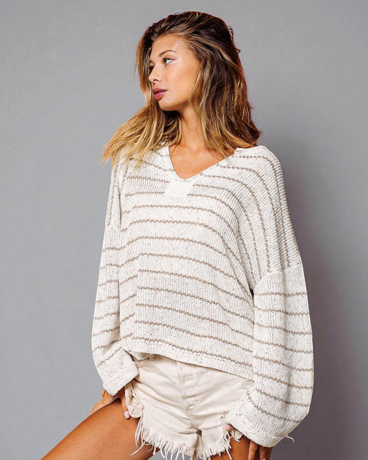 Woman wearing a white and gray striped sweater against a gray background