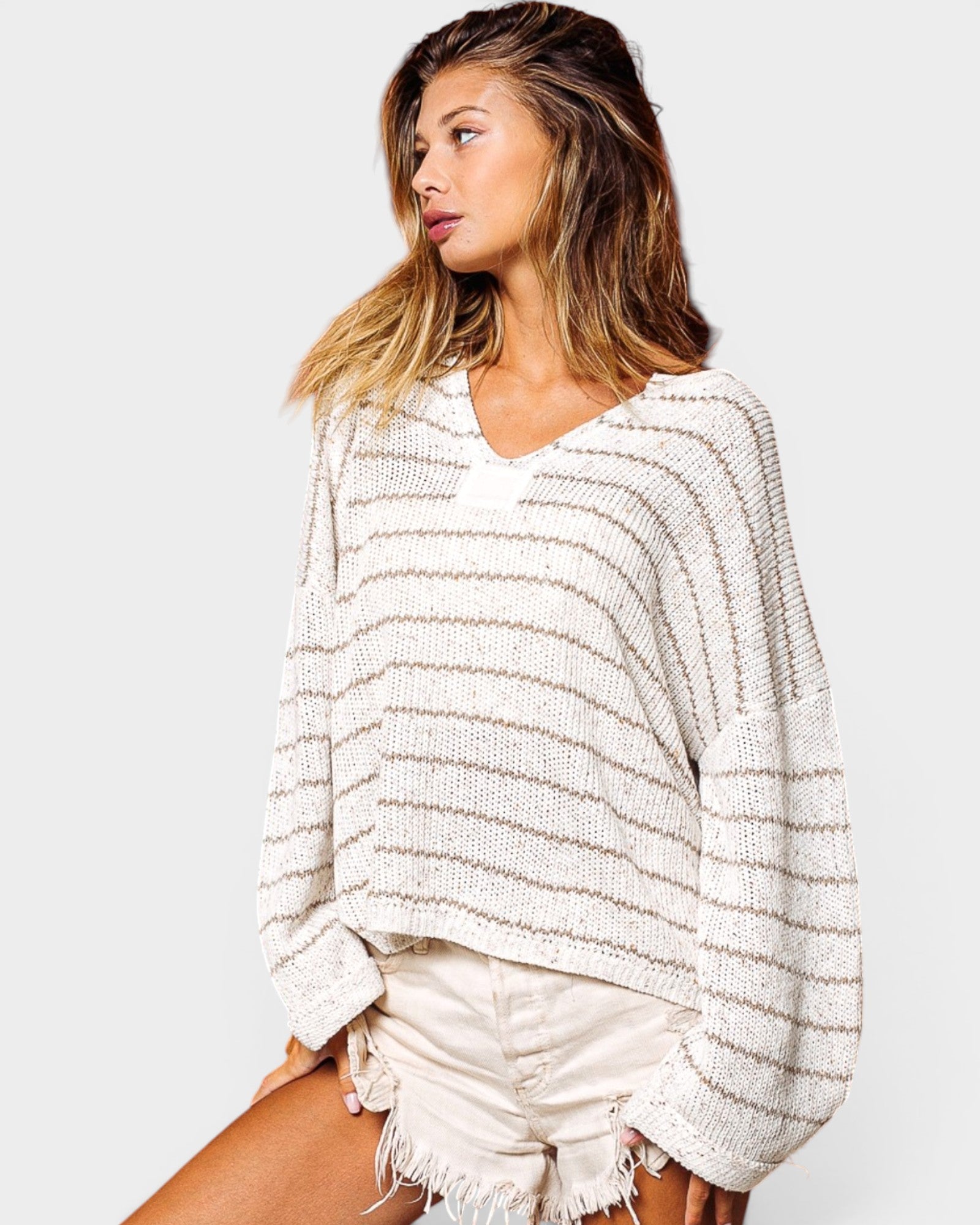 Woman wearing a white and gray striped sweater on a plain background