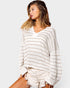 Woman wearing a white and gray striped sweater on a plain background