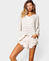 Woman wearing a white striped sweater and shorts on a plain background