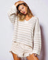 Woman wearing a white knitted sweater and shorts against a light background