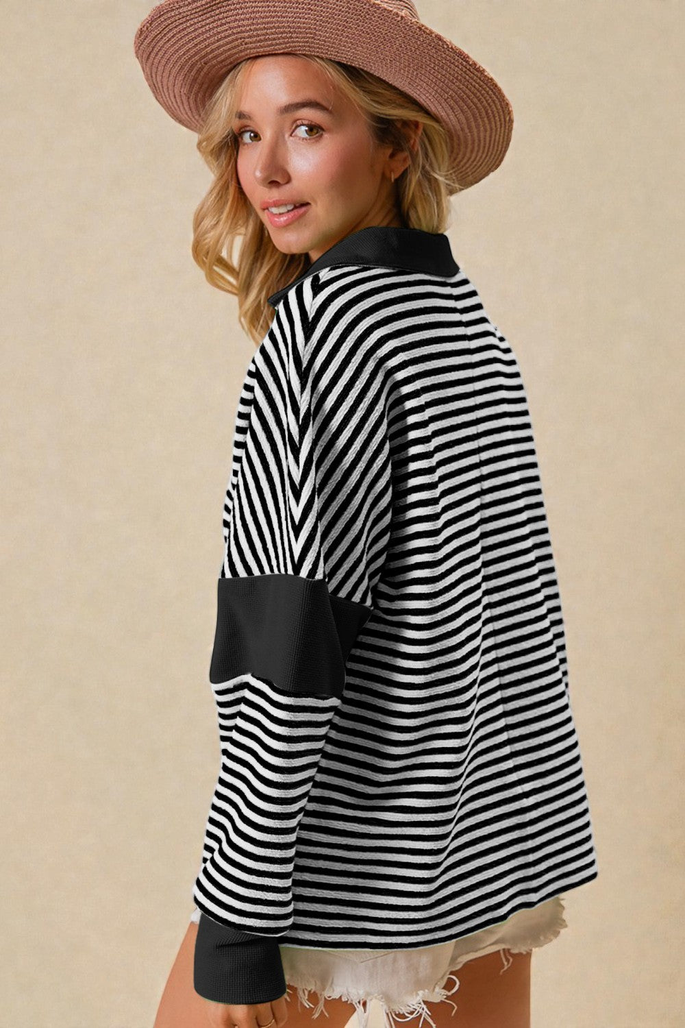 Woman wearing a black and white striped sweater with a beige background