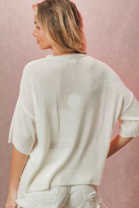 Woman wearing a white sweater against a pink background