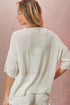 Woman wearing a white sweater against a pink background