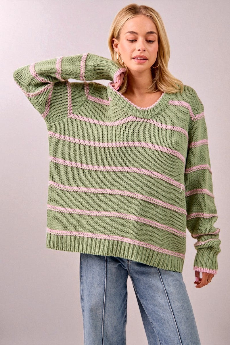 Woman wearing a green and pink striped sweater against a plain background