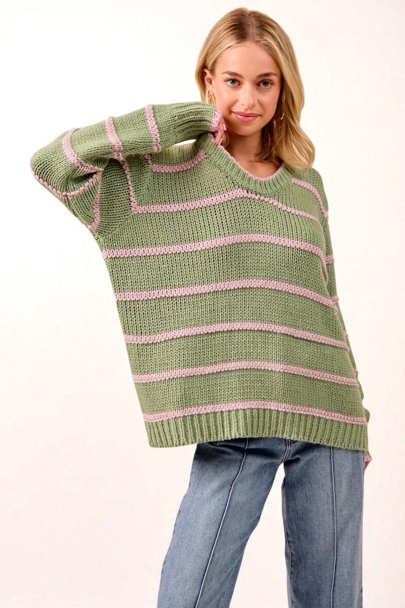 Woman wearing a green and pink striped sweater on a white background