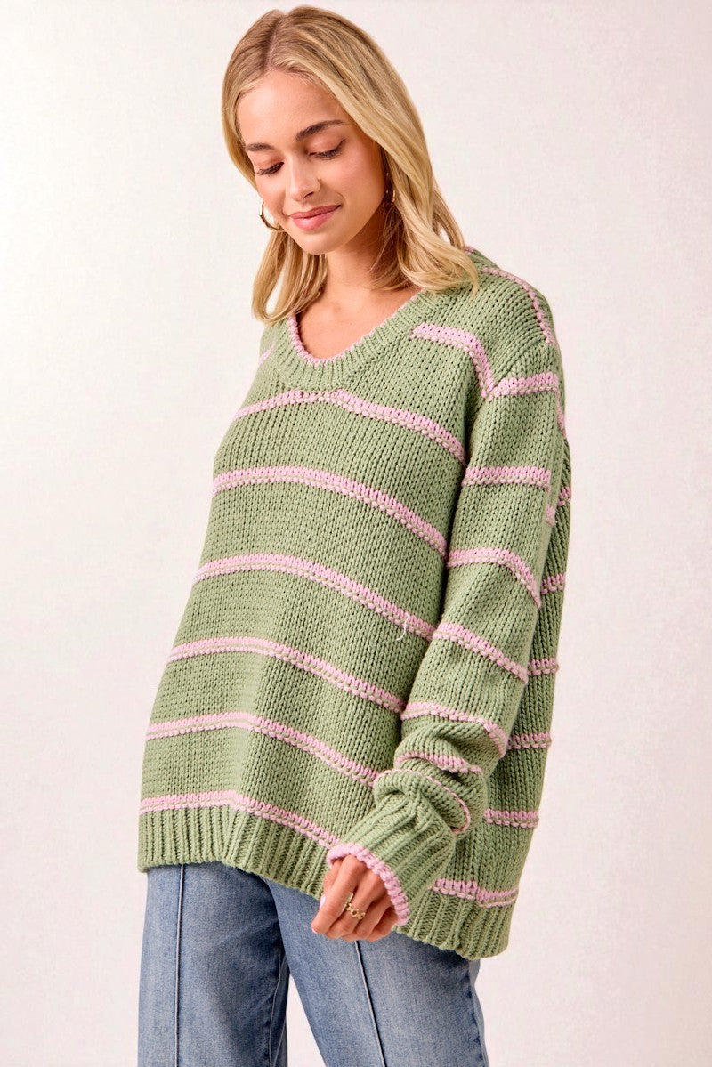Woman wearing a green and pink striped sweater on a white background