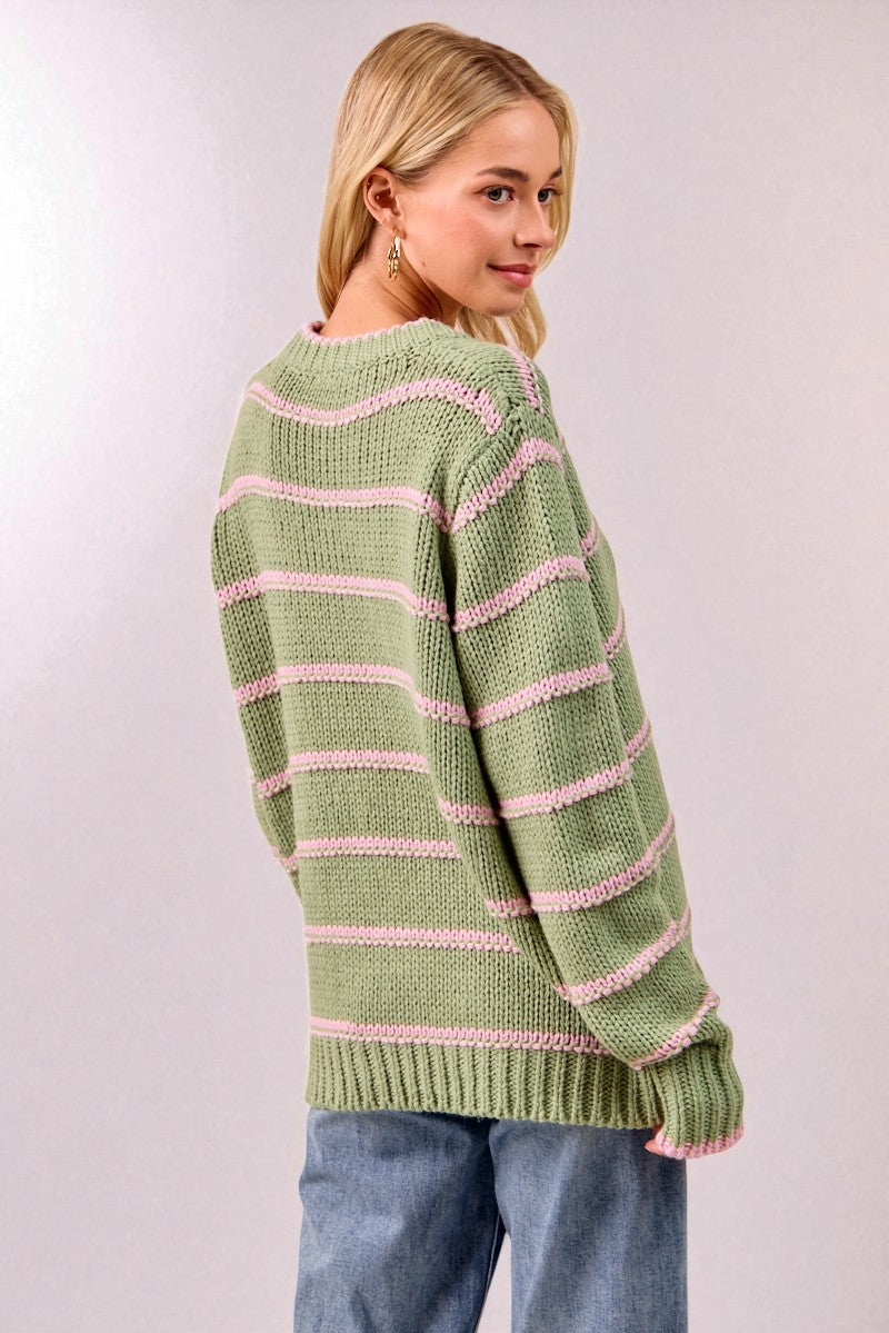 Woman wearing a green and pink striped sweater against a plain background