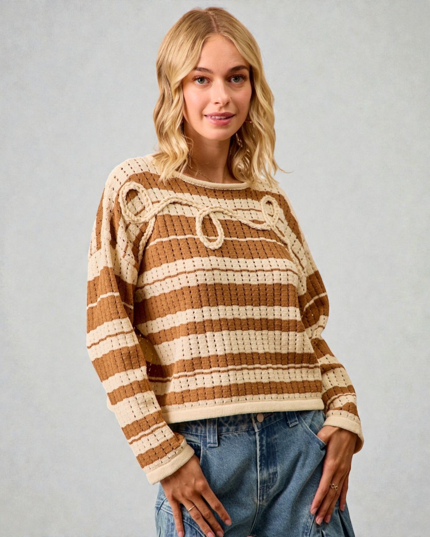 Woman wearing a brown and beige striped sweater against a plain background