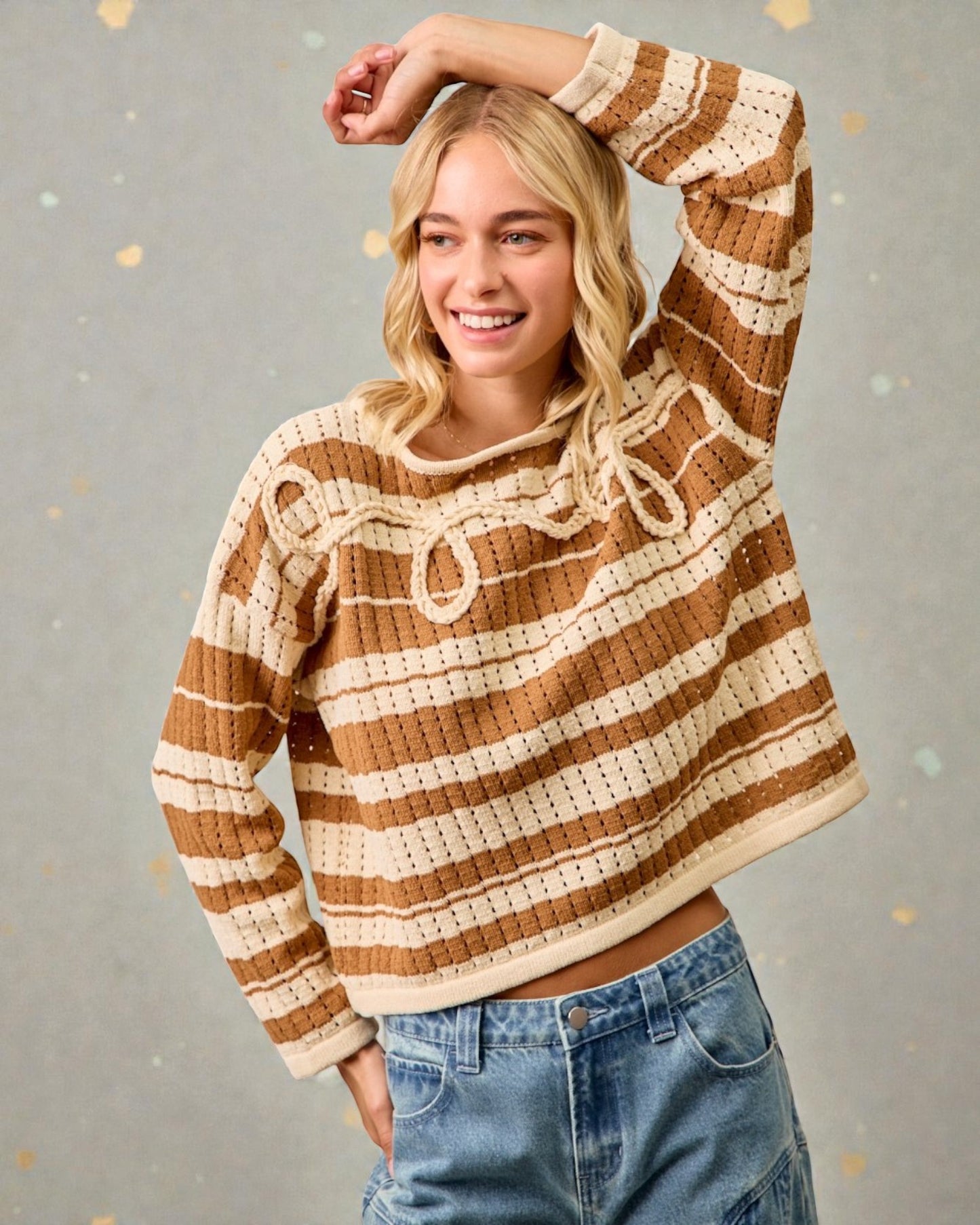 Woman wearing a brown and beige striped sweater with a gray background