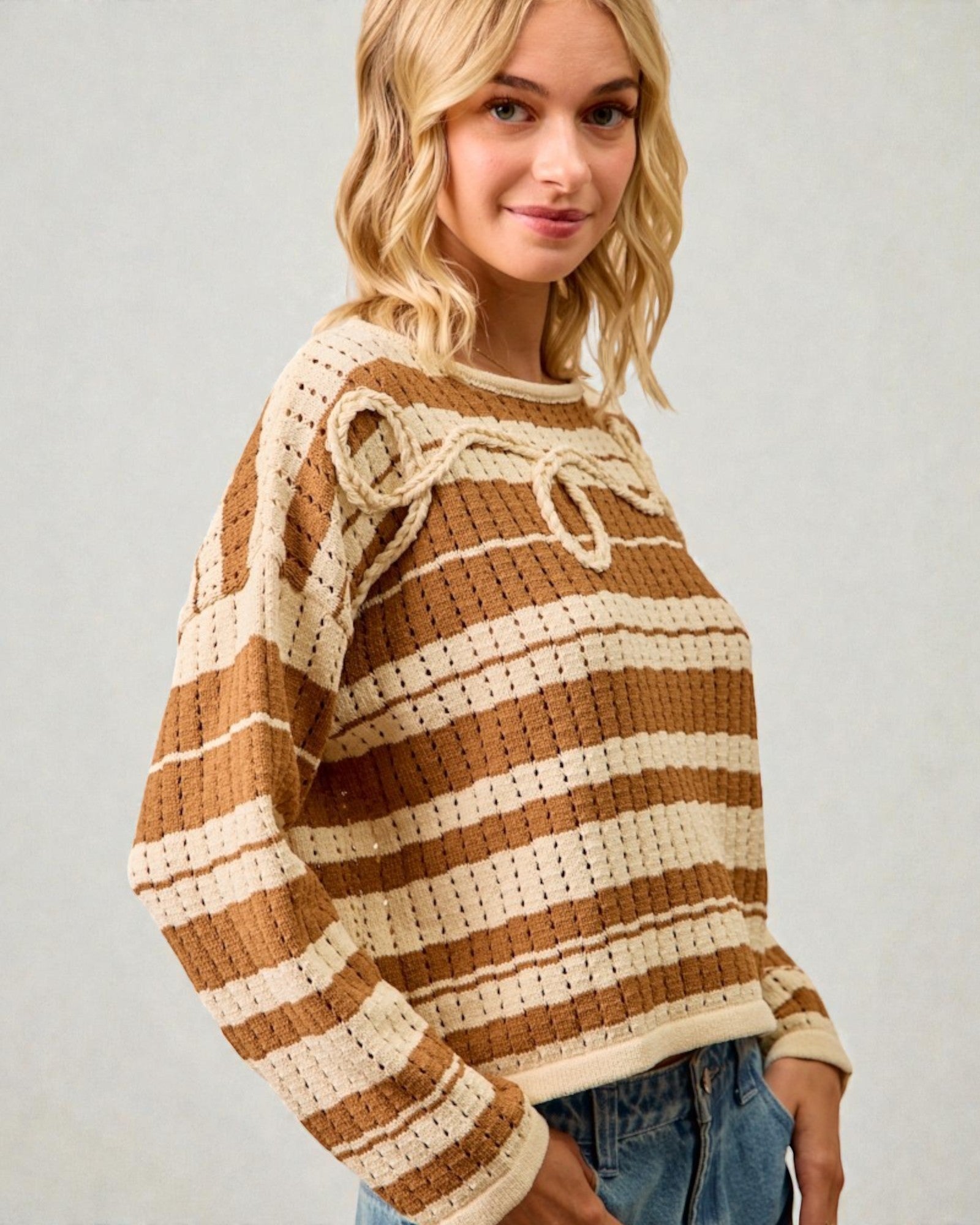 Woman wearing a brown and beige striped sweater against a plain background