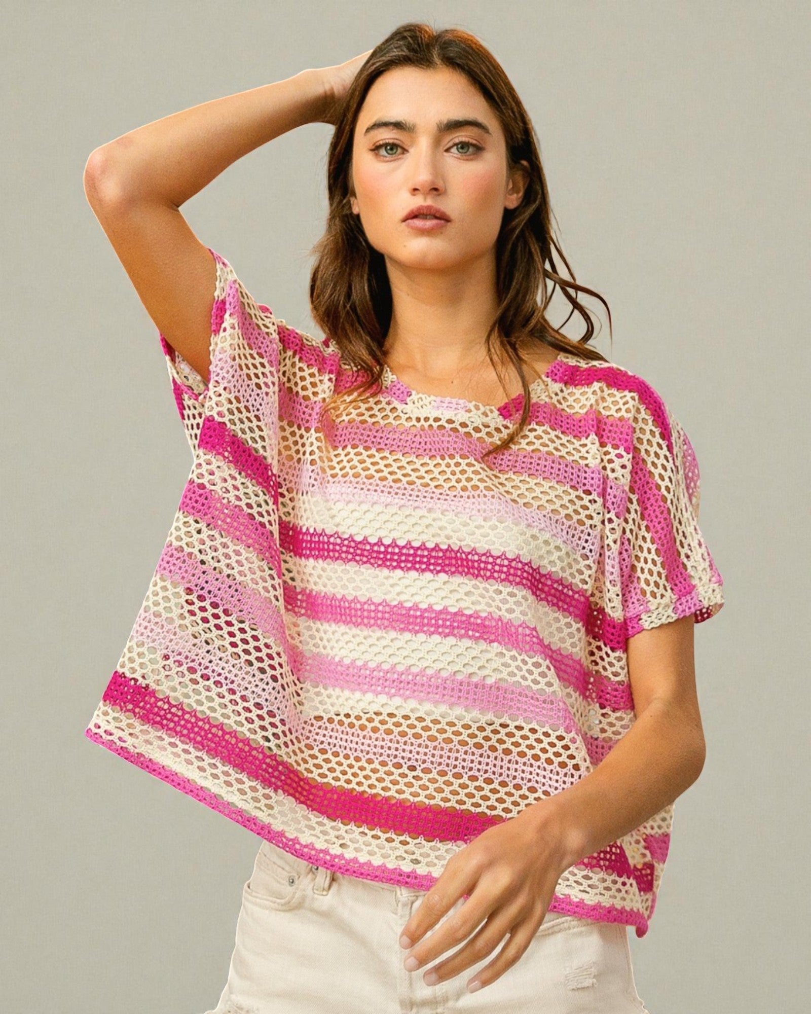 Woman wearing a pink and white striped crochet top against a neutral background