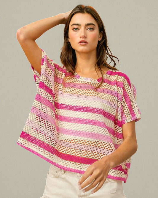 Woman wearing a pink and white striped crochet top against a neutral background