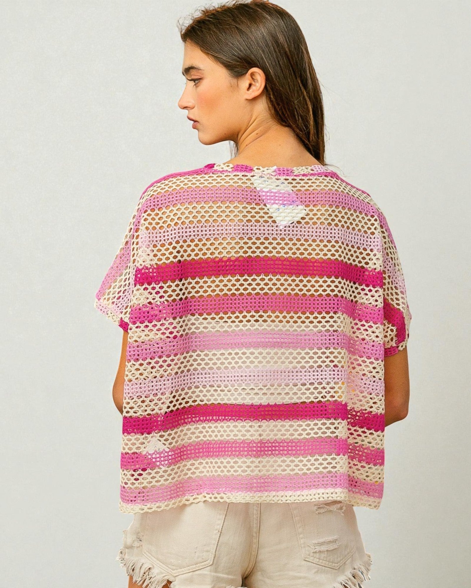 Woman wearing a pink and beige striped crochet top on a plain background