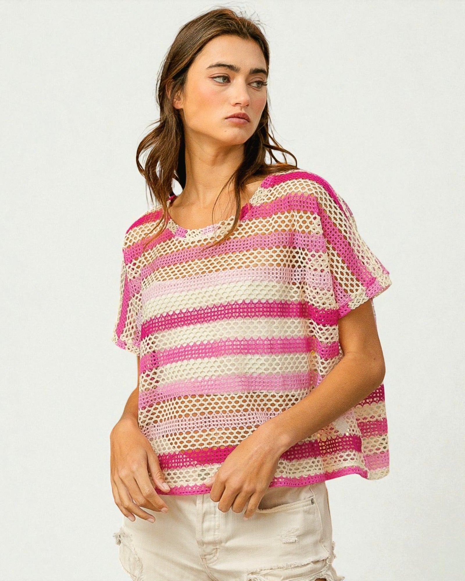 Woman wearing a pink and white striped crochet top on a plain background