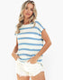 A woman modeling a short-sleeve crewneck top with horizontal blue and off-white stripes, paired with white shorts, against a plain white background.