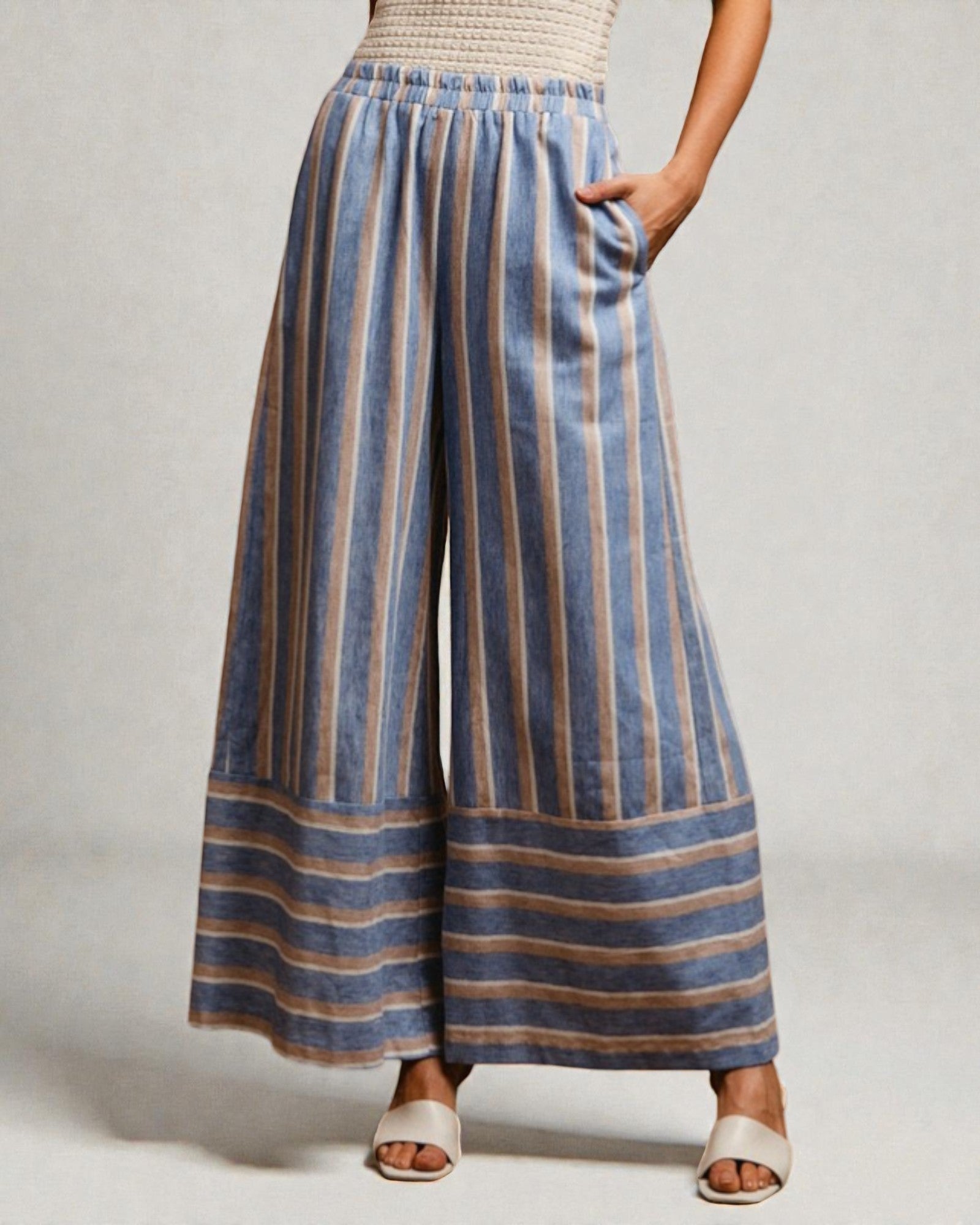 Person wearing blue and beige striped wide-leg pants on a plain background