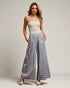 Woman wearing a strapless top and blue striped pants on a plain background
