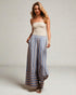 Woman wearing a strapless top and striped pants on a plain background