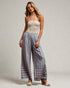 Woman wearing a strapless top and striped pants on a plain background