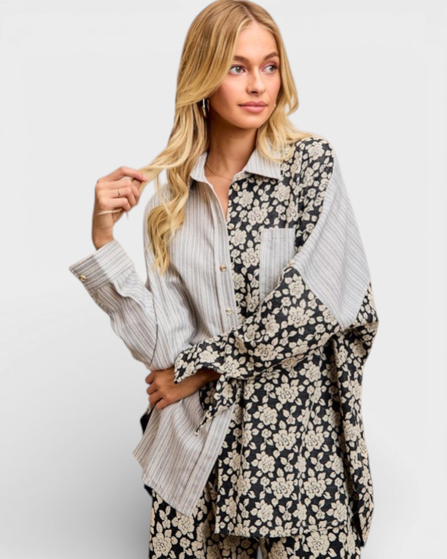 Woman wearing a floral kimono-style garment over a striped shirt on a plain background