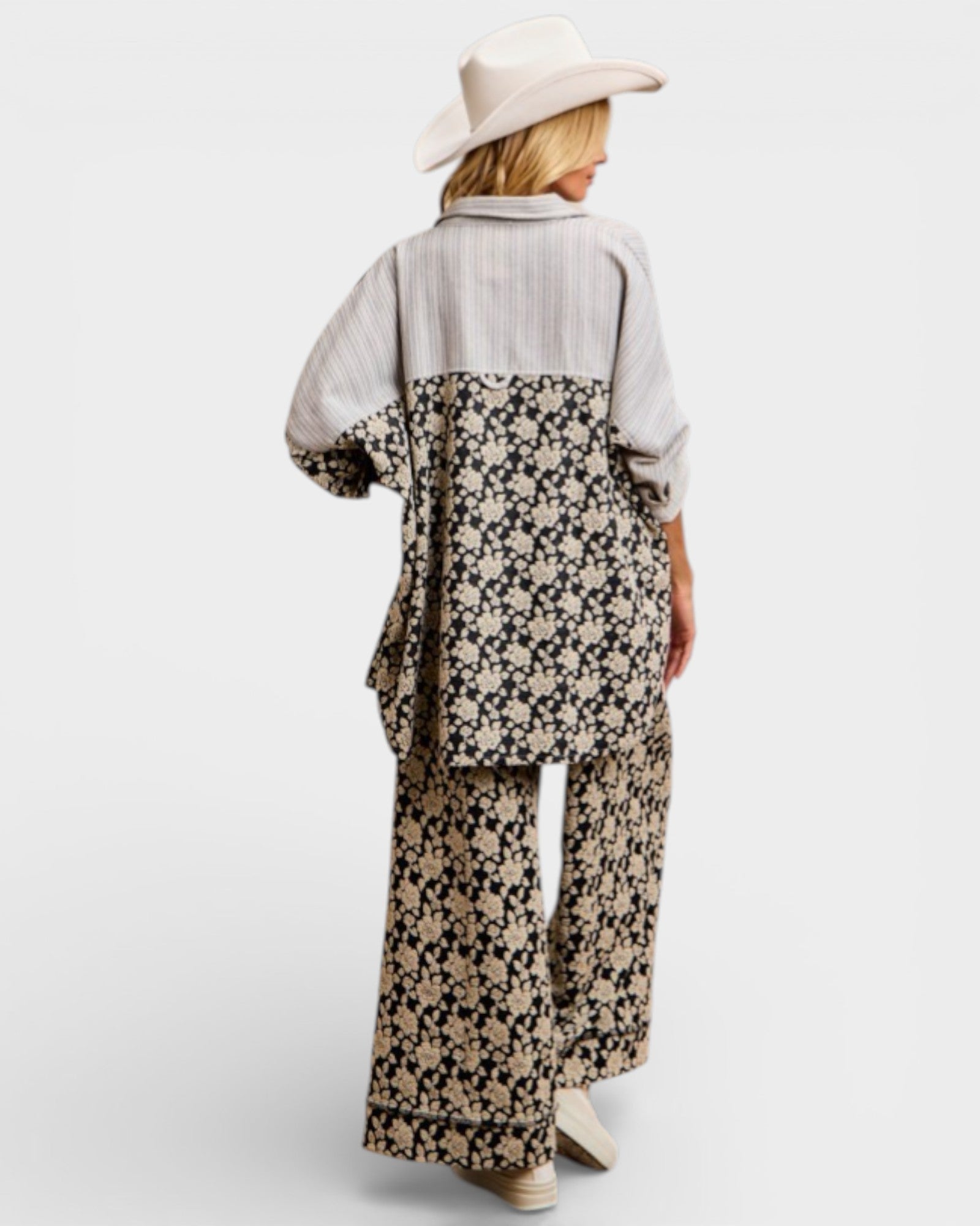 Person wearing a floral dress with a plain shirt underneath on a white background